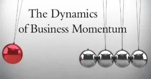 Newton’s cradle showing business momentum concept with one red ball moving against silver balls on a gray background